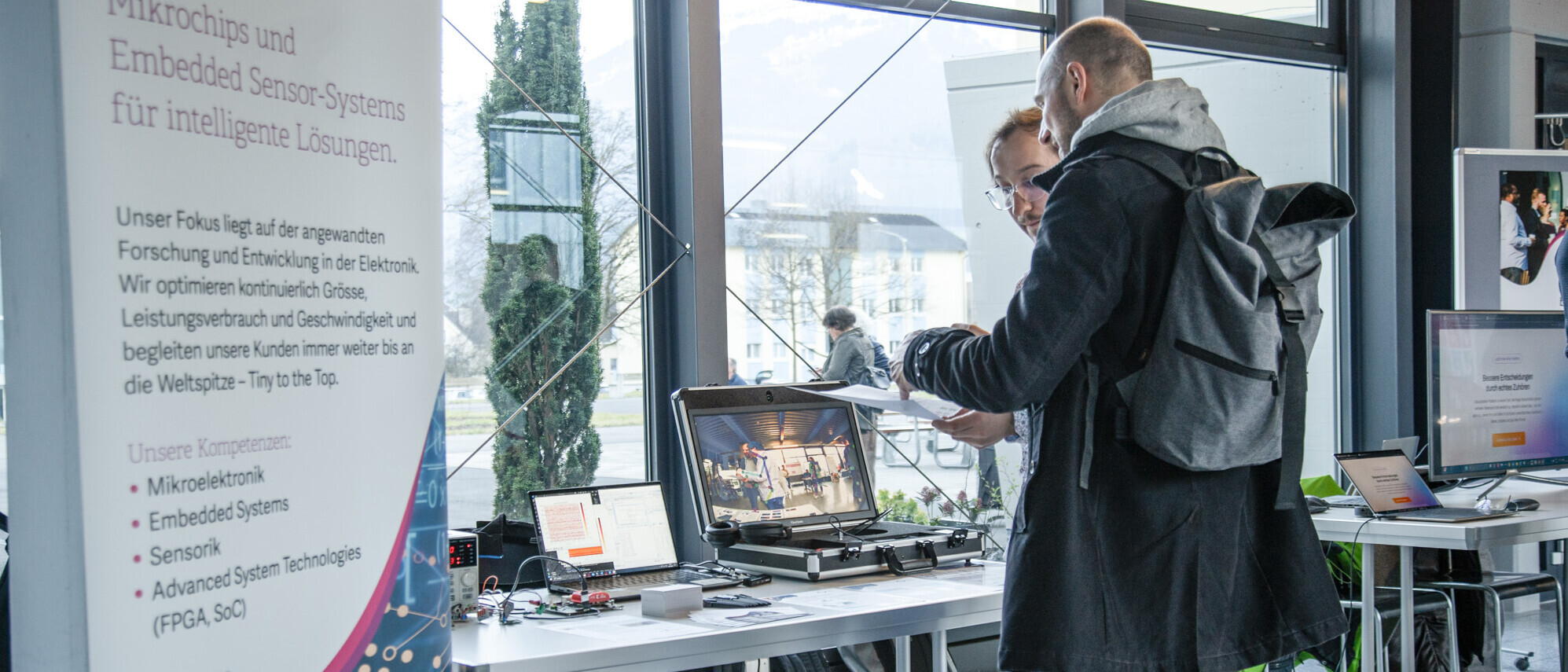 Ein Besucher lässt sich verschiedene KI-Projekte erklären.