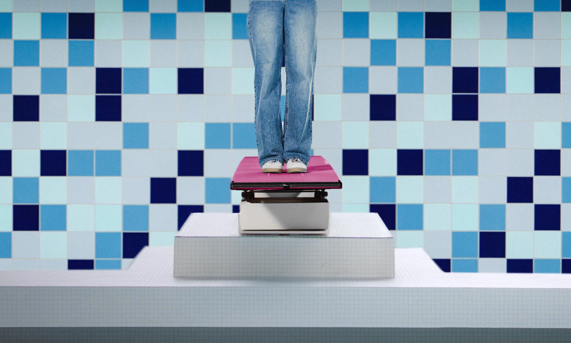 Person steht auf einem Sprungbrett vor einer blau gekachelten Wand