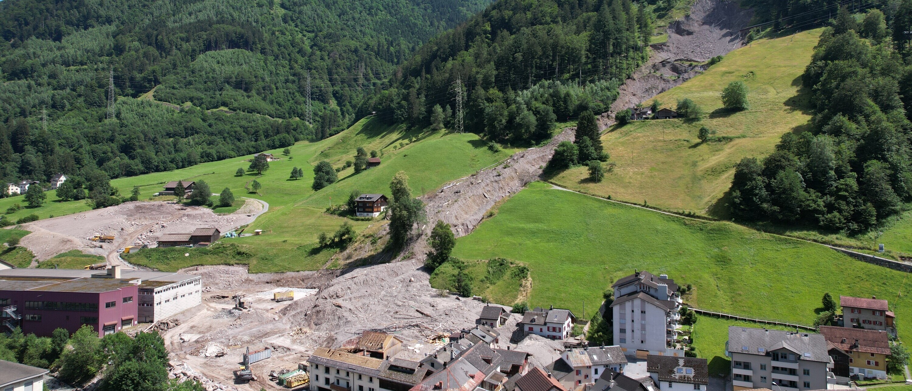 Luftaufnahme der durch die Erdrutsche beschädigten Gebäude und Freiräume im Quartier Plattenau in Schwanden im August 2023.