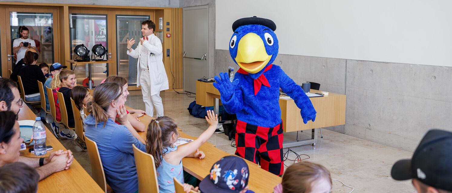 Globi begrüsst Kinder während der interaktiven Energieshow am Tag der offenen Tür.