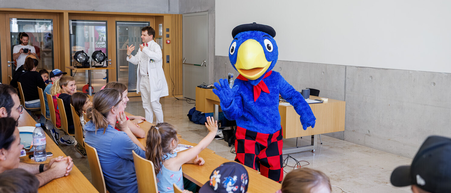 Globi begrüsst Kinder während der interaktiven Energieshow am Tag der offenen Tür.