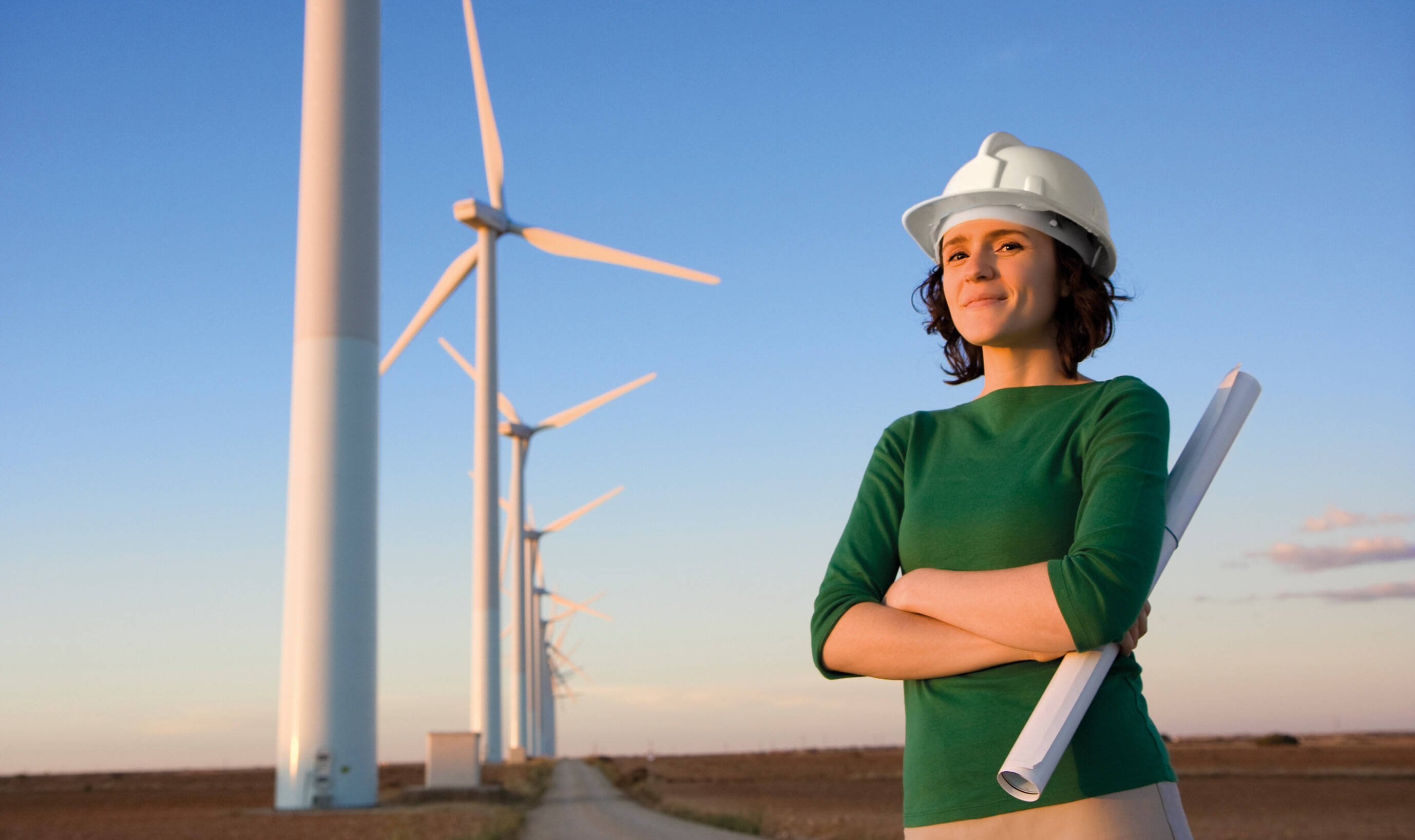 Frau mit Helm vor Windenergie-Anlage