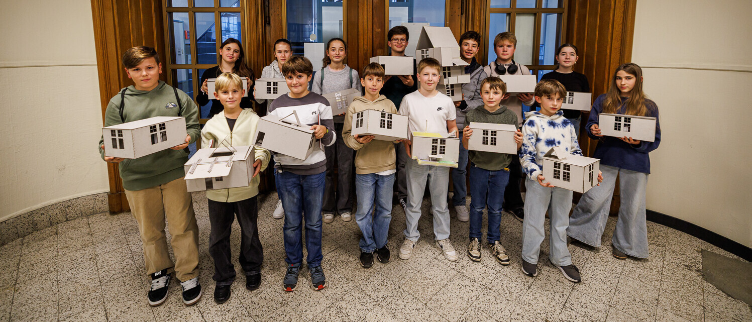 Kinder präsentieren ihr gebautes Haus freudig.
