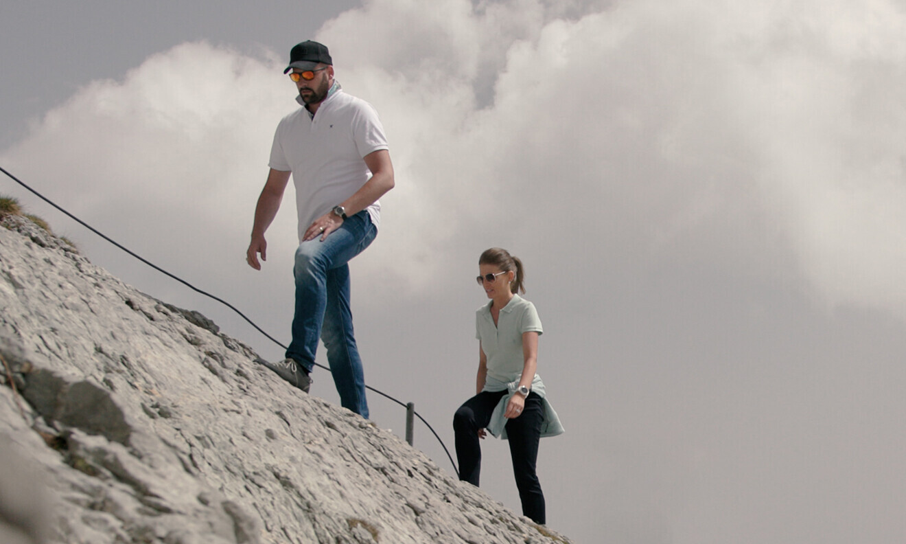 Ein Absolvent und eine Absolventin des Executive MBA beim Aufstieg auf einen Berg. 