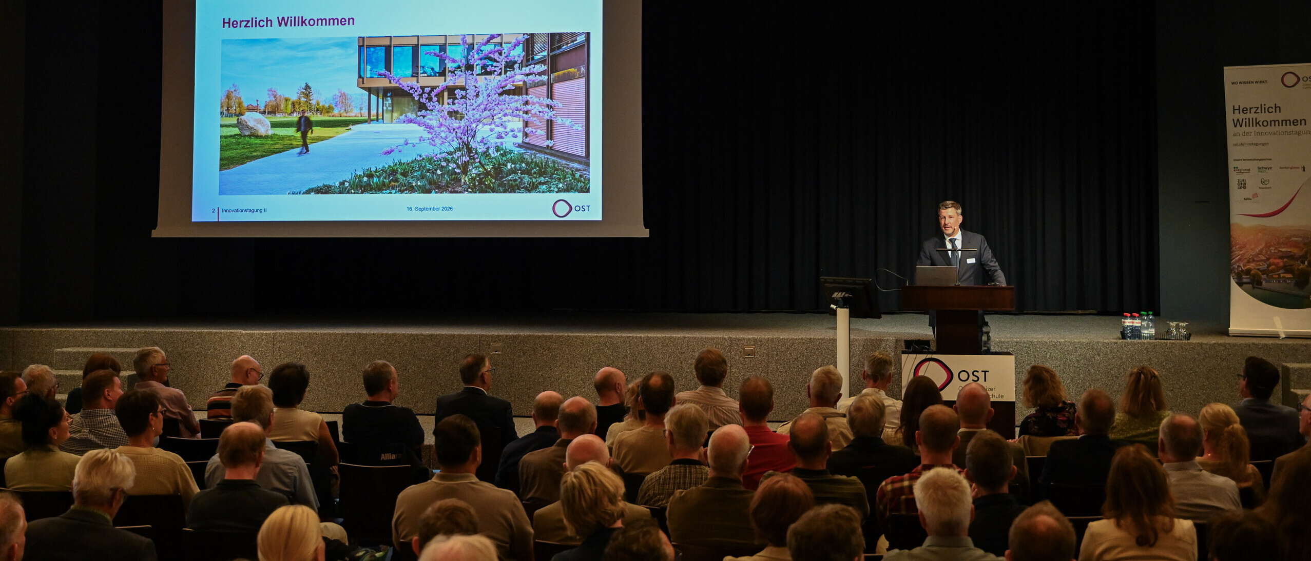 Prof. Hanspeter Keel steht am Rednerpult vor einem Publikum im Saal der Innovationstagung.