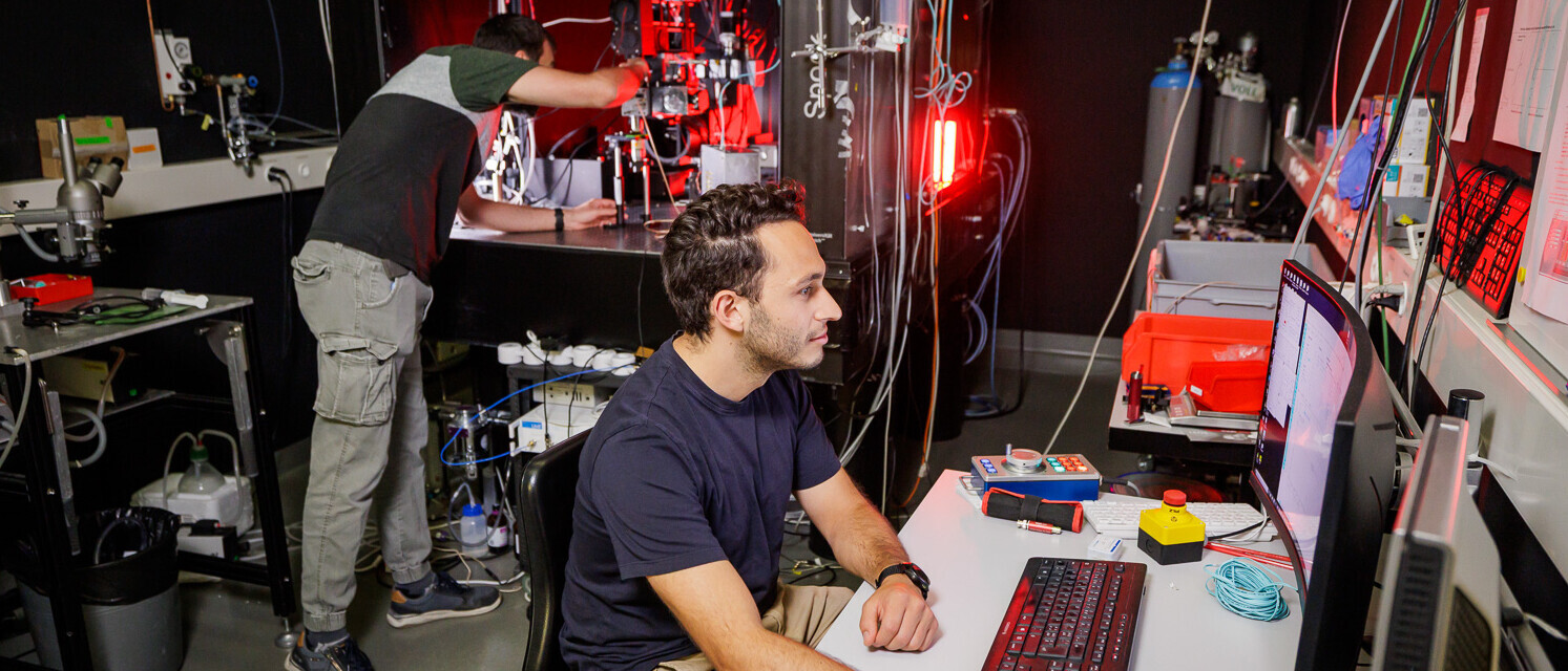 Im Labor arbeiten zwei Männer an diesem Zellmesslaser. Der eine arbeitet am Computer und der andere an der Maschine. 