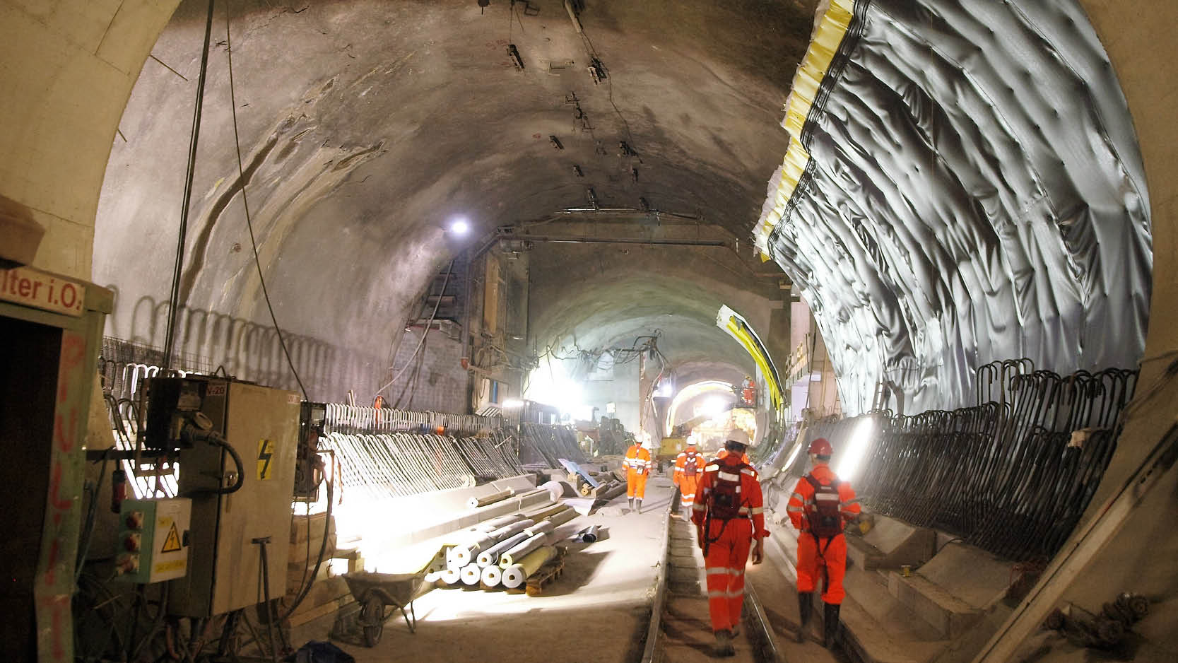 Mehrere Arbeiten in oranger Kleidung arbeiten im Tiefbau (Tunnel)