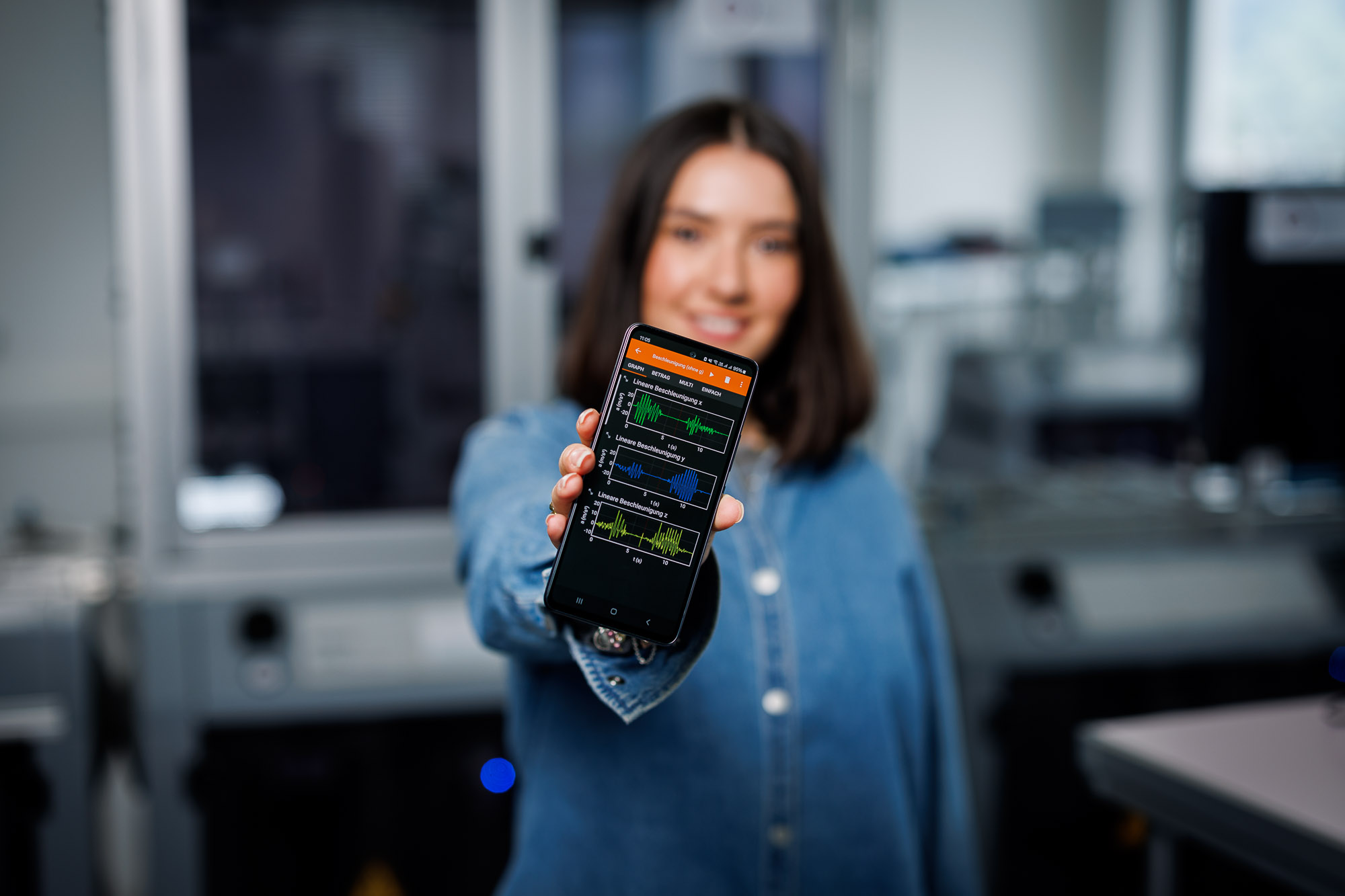 Eine Studentin im Studiengang Mechatronik mit der Vertiefung Data Engineering and Industrial AI streckt Ihr Mobile in die Kamera, das ein von ihr entwickeltes Programm zeigt.