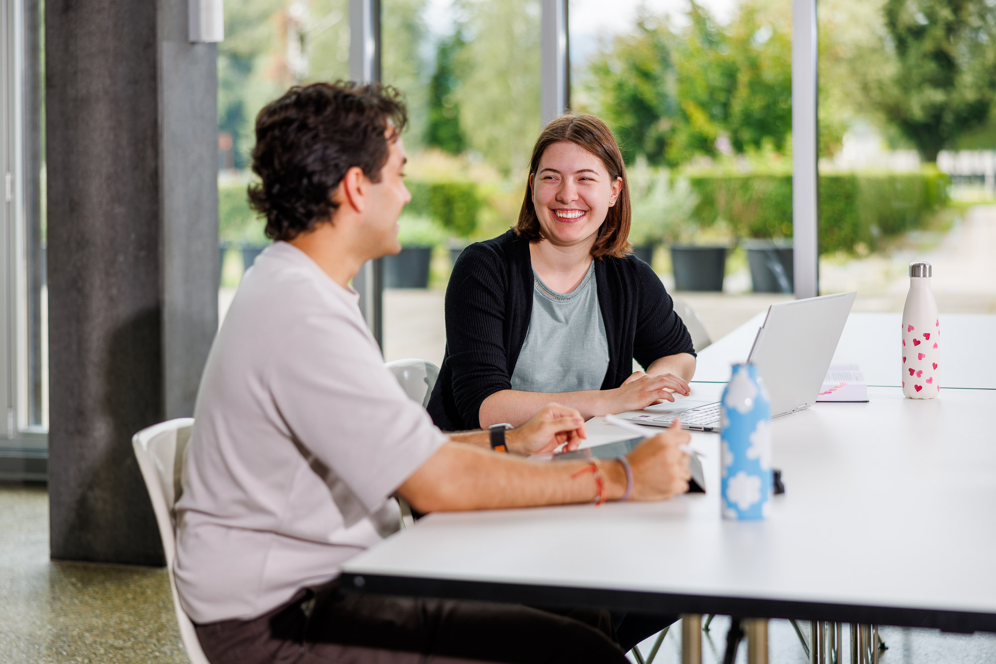 Eine Wirtschaftsinformatik-Studentin und ein Wirtschaftsinformatik-Student unterhalten sich im Unterrichtsraum. 