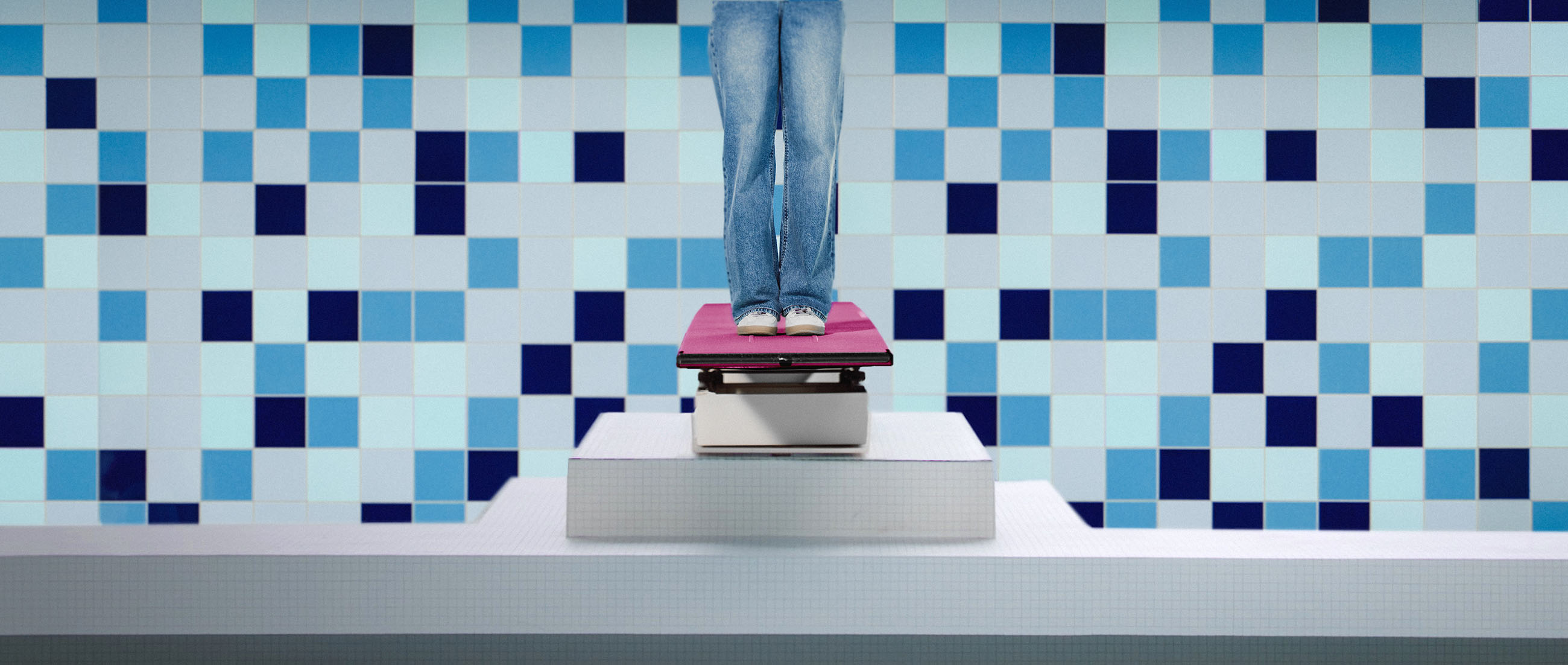 Person steht auf einem Sprungbrett vor einer blau gekachelten Wand