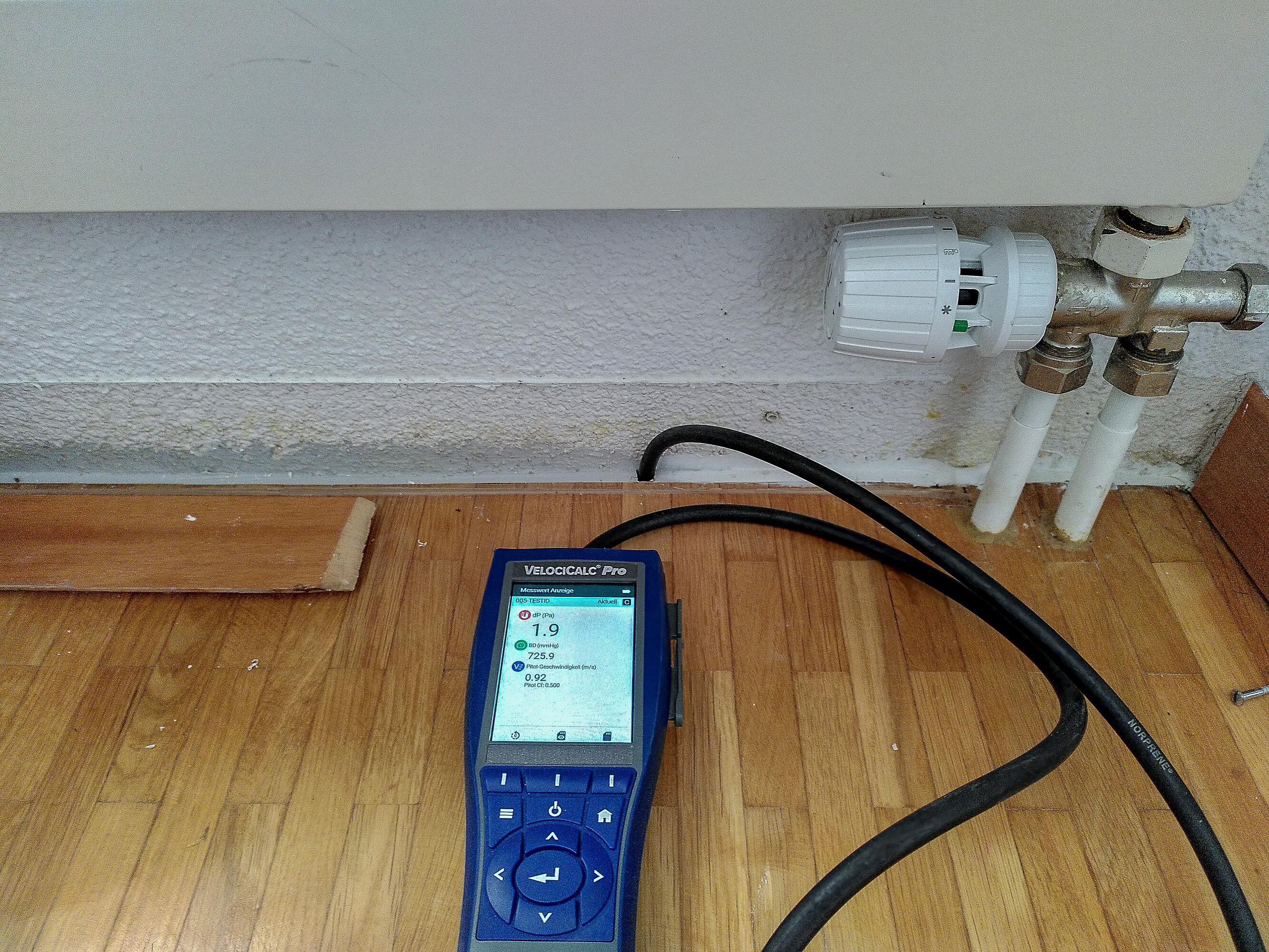 Das kleine blaue Gerät ist hier auf dem Fussboden unterhalb eines Heizungsradiators angebracht, um den Geruch zu finden.  